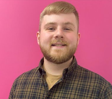 Hunter Kanzelberger (ITA Class of 2020) has light hair and skin, and is wearing a plaid shirt while grinning against a pink background.